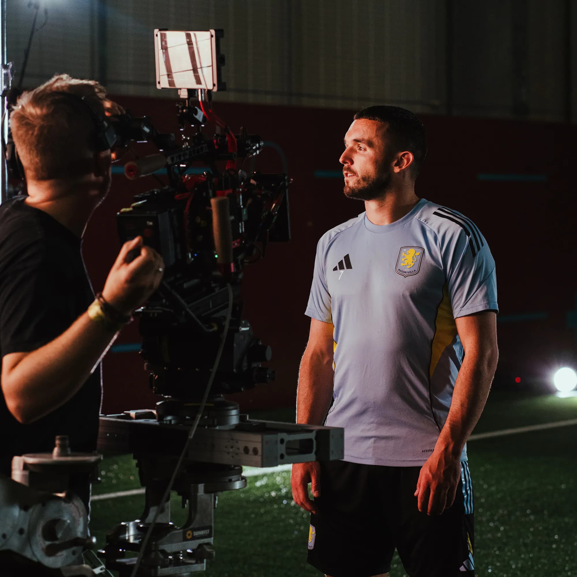 A camera operator films an Aston Villa player under studio lights on the Xapo Bank shoot.